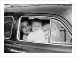 Mother holds crying son in her lap in car, ca. 1954 by Anonymous