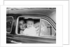 Mother holds crying son in her lap in car, ca. 1954 by Anonymous