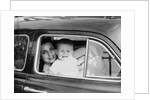 Mother holds crying son in her lap in car, ca. 1954 by Anonymous