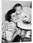 Baby boy hugging mother at dinner time, ca. 1953 by Anonymous