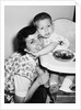 Baby boy hugging mother at dinner time, ca. 1953 by Anonymous