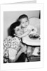Baby boy hugging mother at dinner time, ca. 1953 by Anonymous