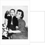 Little boy holding football with his mother, ca. 1955 by Anonymous
