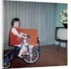 Young girl rides her new tricycle in the house, ca. 1967 by Anonymous
