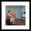 Young girl rides her new tricycle in the house, ca. 1967 by Anonymous