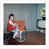Young girl rides her new tricycle in the house, ca. 1967 by Anonymous