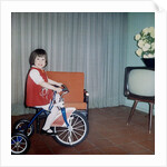 Young girl rides her new tricycle in the house, ca. 1967 by Anonymous