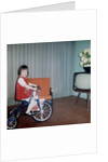 Young girl rides her new tricycle in the house, ca. 1967 by Anonymous