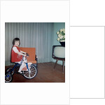 Young girl rides her new tricycle in the house, ca. 1967 by Anonymous