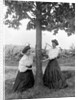 Two women chase each other around a tree, ca. 1910 by Anonymous