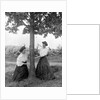 Two women chase each other around a tree, ca. 1910 by Anonymous