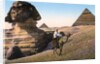 Man riding a camel in front of the Sphinx and pyramids by Anonymous