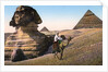 Man riding a camel in front of the Sphinx and pyramids by Anonymous
