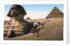 Man riding a camel in front of the Sphinx and pyramids by Anonymous