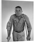 1960s man walking on crutches looking at camera by Anonymous