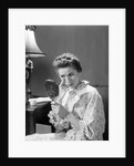 1950s 1960s woman in nightgown holding mirror look at eye wrinkles aging beauty cosmetic serious concerned expression by Anonymous