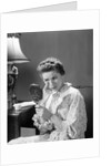 1950s 1960s woman in nightgown holding mirror look at eye wrinkles aging beauty cosmetic serious concerned expression by Anonymous