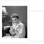 1950s 1960s woman in nightgown holding mirror look at eye wrinkles aging beauty cosmetic serious concerned expression by Anonymous
