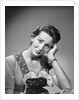 1950s housewife woman in print apron hand up to temple headache pain sad depressed facial expression worried serious looking at camera by Anonymous