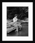 1920s 1930s woman sitting on rock by side of stream wearing waders putting fly on tippet by Anonymous