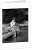 1920s 1930s woman sitting on rock by side of stream wearing waders putting fly on tippet by Anonymous