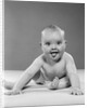 1950s portrait of baby sitting and sticking tongue out looking at camera by Anonymous