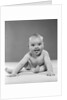 1950s portrait of baby sitting and sticking tongue out looking at camera by Anonymous