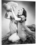 1950s young woman wearing sexy lingerie kneeling on leopard skin holding fluffy dog by Anonymous