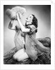 1950s young woman wearing sexy lingerie kneeling on leopard skin holding fluffy dog by Anonymous