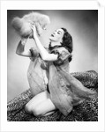 1950s young woman wearing sexy lingerie kneeling on leopard skin holding fluffy dog by Anonymous