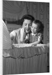 1950s mother & daughter admiring baby in bassinet by Anonymous