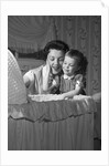 1950s mother & daughter admiring baby in bassinet by Anonymous