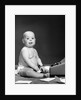 1950s 1960s baby in diaper sticking out tongue holding glasses sitting before adding machine looking at camera by Anonymous