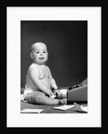 1950s 1960s baby in diaper sticking out tongue holding glasses sitting before adding machine looking at camera by Anonymous