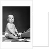 1950s 1960s baby in diaper sticking out tongue holding glasses sitting before adding machine looking at camera by Anonymous