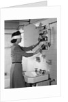 1940s woman wearing blindfold reaching into bathroom medicine cabinet by Anonymous
