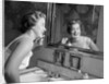 1950s smiling woman looking into bathroom mirror brushing teeth by Anonymous