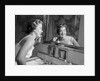 1950s smiling woman looking into bathroom mirror brushing teeth by Anonymous