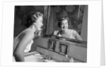 1950s smiling woman looking into bathroom mirror brushing teeth by Anonymous