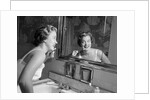 1950s smiling woman looking into bathroom mirror brushing teeth by Anonymous
