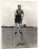 1930s 1940s smiling happy boy wearing striped shirt & short pants walking on pair of stilts looking at camera by Anonymous