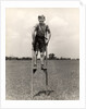 1930s 1940s smiling happy boy wearing striped shirt & short pants walking on pair of stilts looking at camera by Anonymous