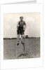 1930s 1940s smiling happy boy wearing striped shirt & short pants walking on pair of stilts looking at camera by Anonymous
