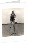 1930s 1940s smiling happy boy wearing striped shirt & short pants walking on pair of stilts looking at camera by Anonymous