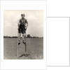 1930s 1940s smiling happy boy wearing striped shirt & short pants walking on pair of stilts looking at camera by Anonymous