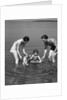1930s family father mother daughter son with rubber inner tube wading in seashore water by Anonymous