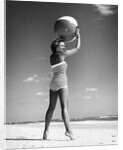1960s woman in stripes swim suit bathing holding beach ball standing on tip toes by Anonymous