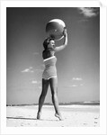 1960s woman in stripes swim suit bathing holding beach ball standing on tip toes by Anonymous