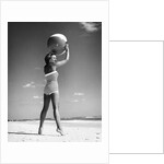 1960s woman in stripes swim suit bathing holding beach ball standing on tip toes by Anonymous