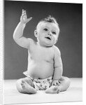 1950s portrait of baby sitting one arm raised waving by Anonymous